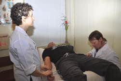 Picture of two student practitioners treating a patient in the student acpuncture clinic.