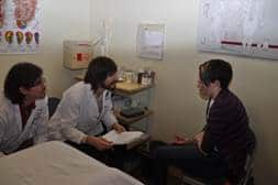 Picture of two student practitioners talking to a patient in the student acpuncture clinic.